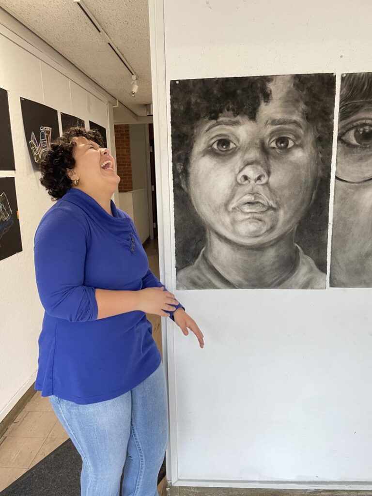 Ileana Kuran laughing next to her erasure self portrait.